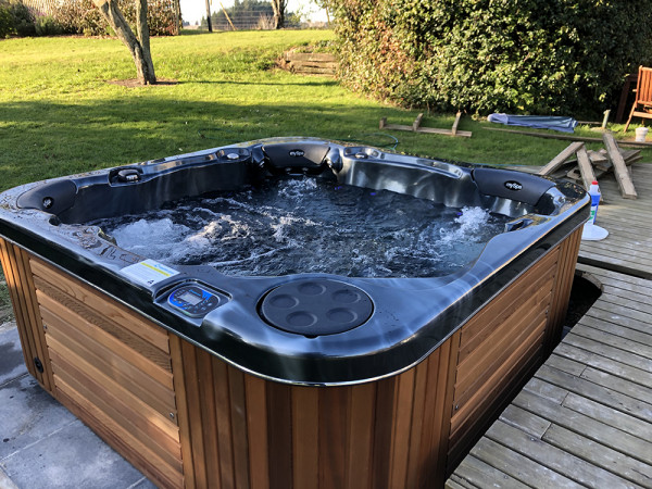 Spa pool with surrounding deck and lush green grass in background 