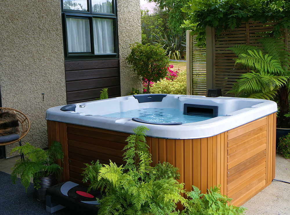 Spa pool in backyard with lush green ferns